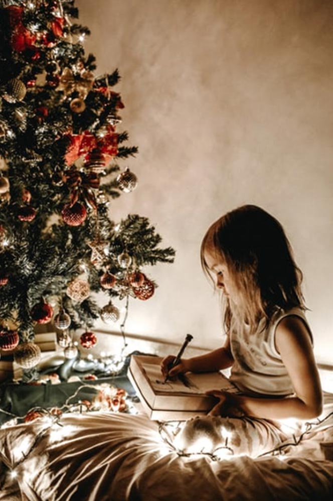 GIRL WRITING UNDER CHRISTMAS TREE
